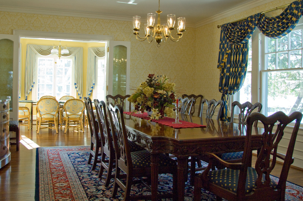 Immagine di un'ampia sala da pranzo aperta verso la cucina chic con pareti gialle e pavimento in legno massello medio