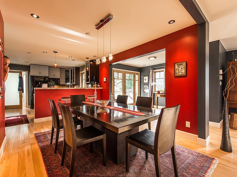 Cette photo montre une salle à manger ouverte sur la cuisine tendance de taille moyenne avec un mur rouge et parquet clair.