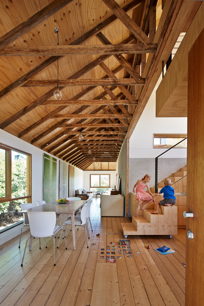 Foto di una sala da pranzo aperta verso la cucina country con pareti bianche e pavimento in legno massello medio