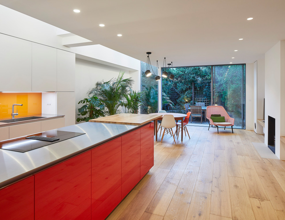 Große Moderne Wohnküche mit weißer Wandfarbe, hellem Holzboden, Kamin, verputzter Kaminumrandung und beigem Boden in London