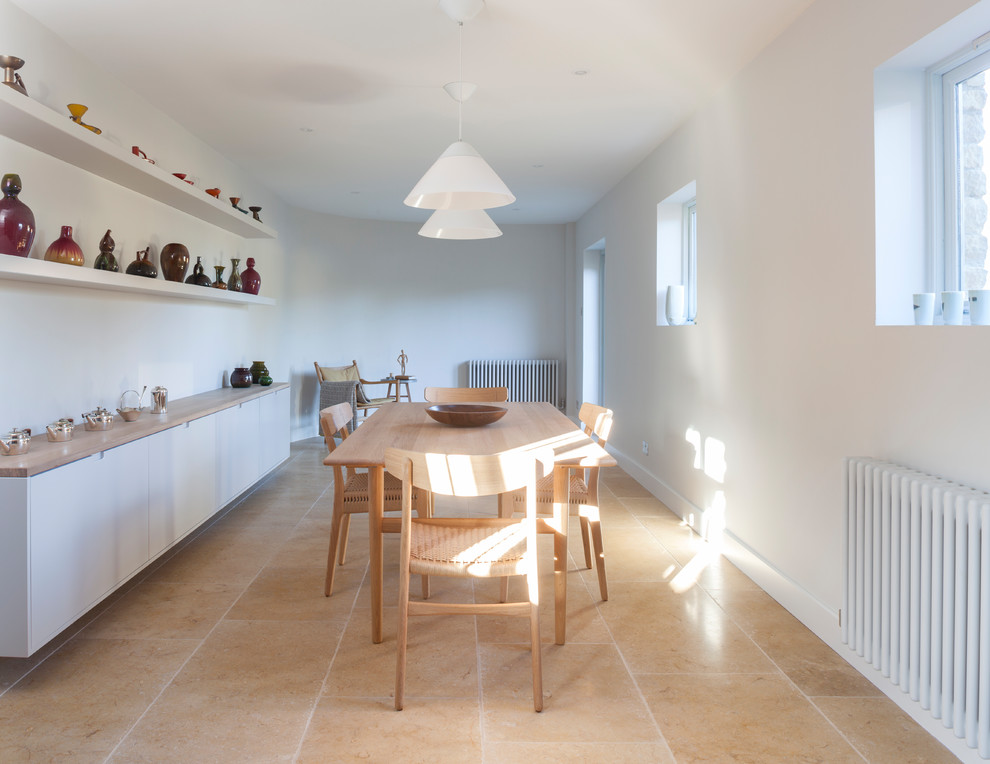 Immagine di una sala da pranzo aperta verso la cucina design di medie dimensioni con pareti bianche, pavimento in pietra calcarea, nessun camino e pavimento beige