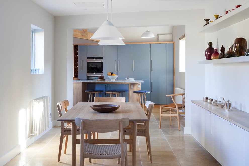 Réalisation d'une salle à manger ouverte sur la cuisine design de taille moyenne avec un mur blanc, un sol en calcaire, aucune cheminée et un sol beige.