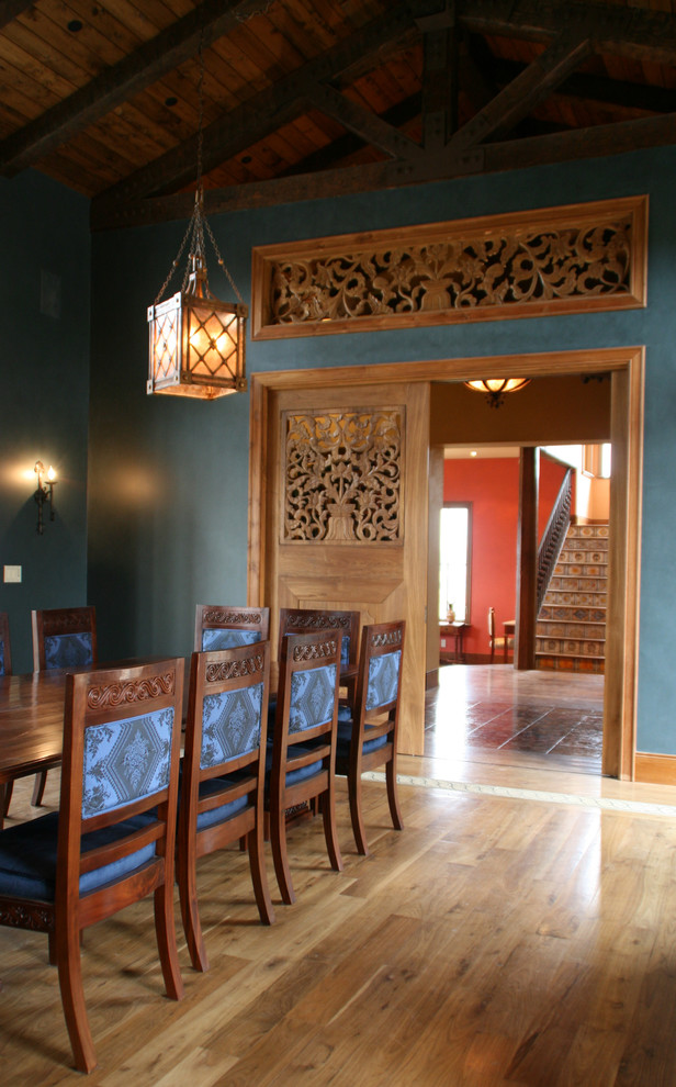 Idée de décoration pour une salle à manger méditerranéenne avec un sol en bois brun et un mur vert.