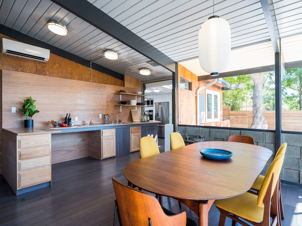Aménagement d'une salle à manger ouverte sur la cuisine rétro avec un mur multicolore, parquet foncé et un sol marron.