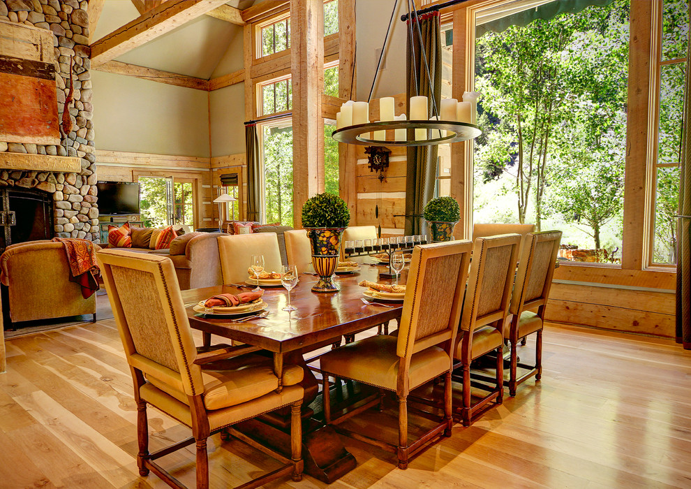 Exemple d'une très grande salle à manger ouverte sur le salon craftsman avec un mur vert, parquet clair, une cheminée standard et un manteau de cheminée en pierre.