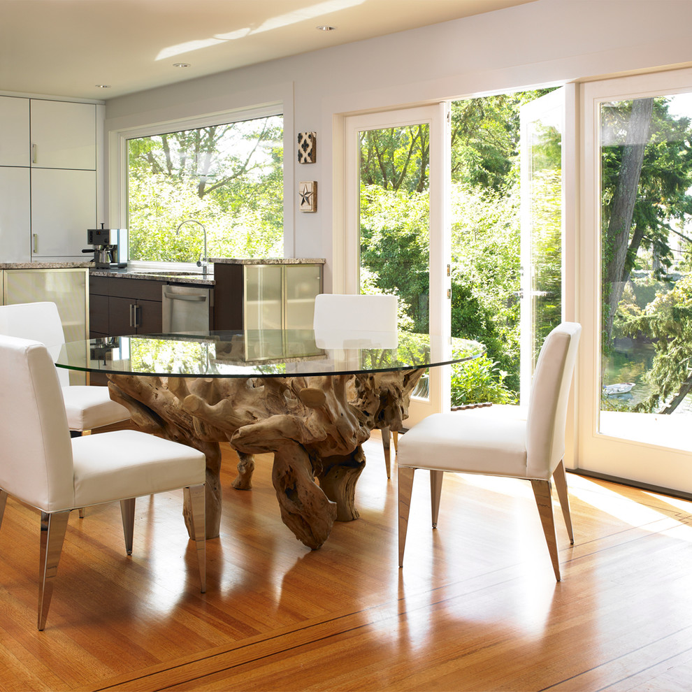 Immagine di una sala da pranzo aperta verso la cucina moderna con pareti bianche e pavimento in legno massello medio