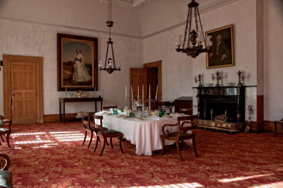 Foto di una grande sala da pranzo aperta verso il soggiorno tradizionale con pareti beige, moquette, camino classico e pavimento rosso