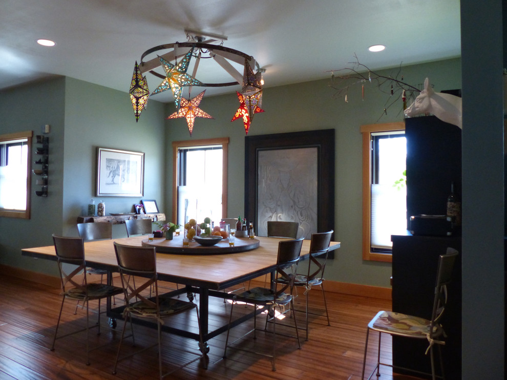 Cette image montre une grande salle à manger ouverte sur le salon bohème avec un mur vert, parquet en bambou, une cheminée standard, un manteau de cheminée en pierre et un sol marron.