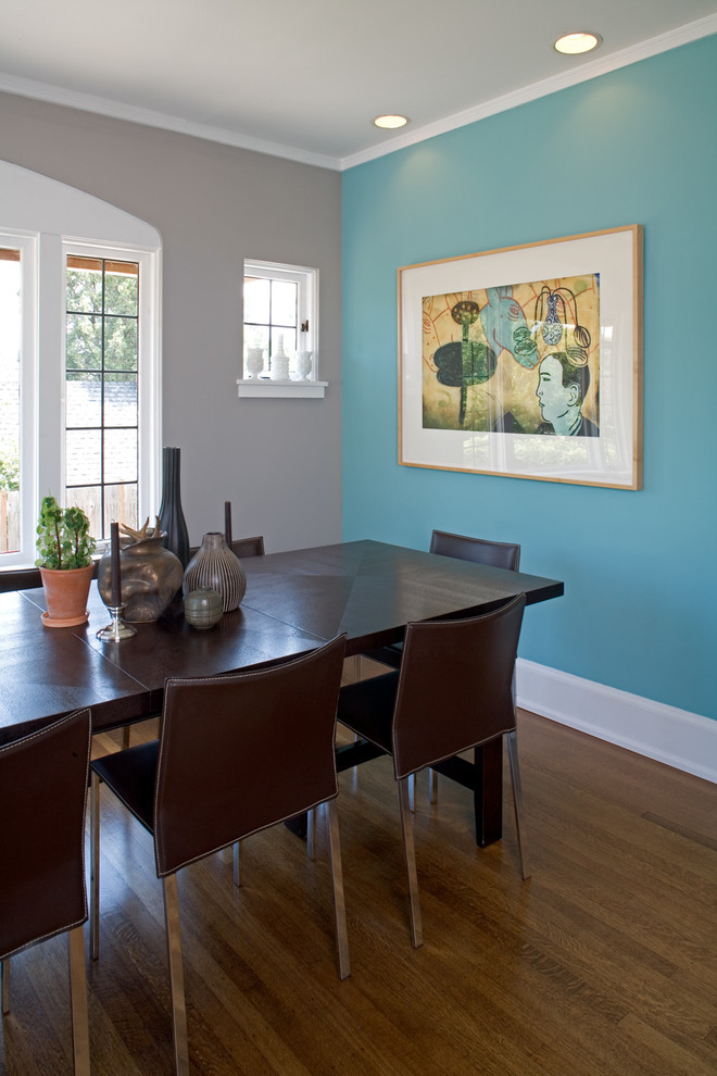 Modelo de comedor bohemio grande cerrado con paredes azules y suelo de madera en tonos medios