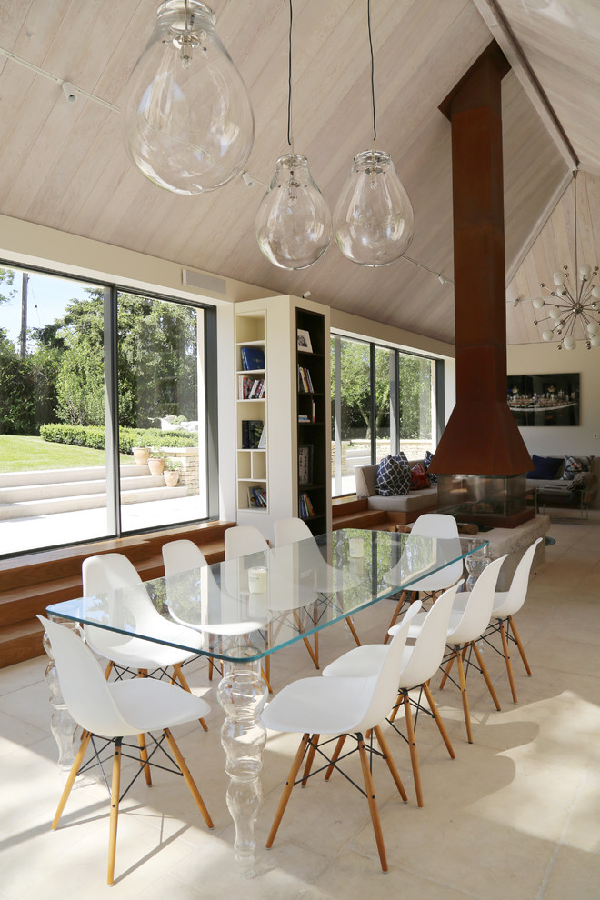 Cette image montre une salle à manger ouverte sur le salon design de taille moyenne avec un manteau de cheminée en pierre, un sol beige, un mur beige et une cheminée double-face.