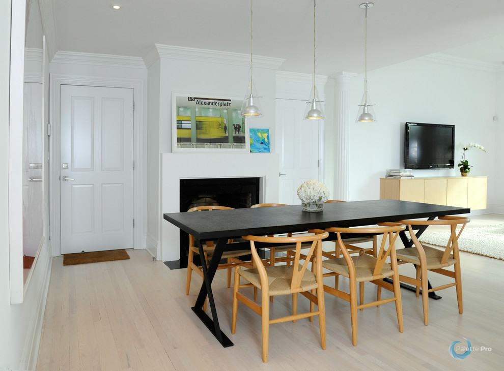 Immagine di una grande sala da pranzo aperta verso la cucina moderna con pareti bianche, parquet chiaro e camino classico