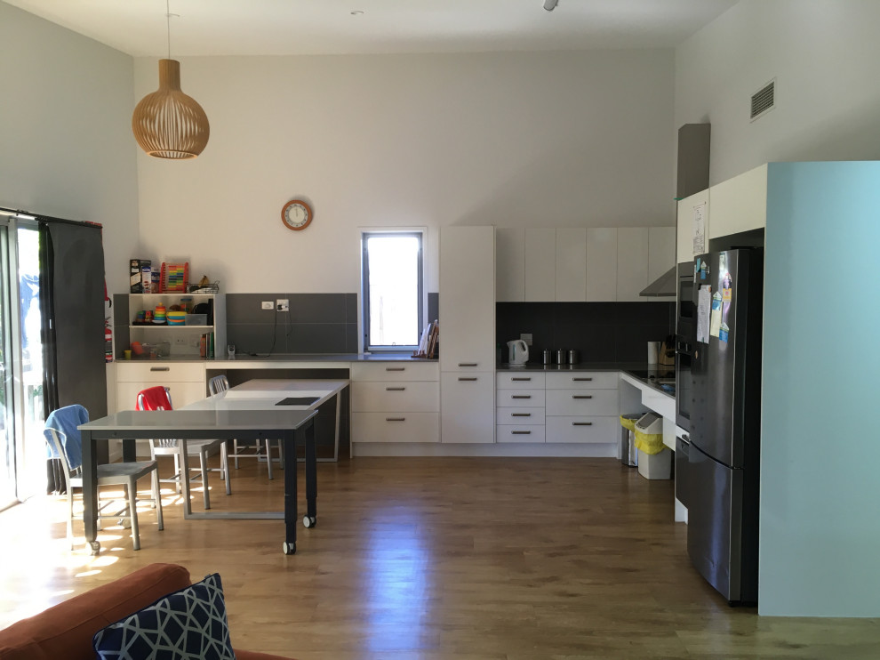 Immagine di una sala da pranzo aperta verso la cucina minimal di medie dimensioni con pareti bianche, pavimento in compensato, pavimento marrone, soffitto a volta e pannellatura