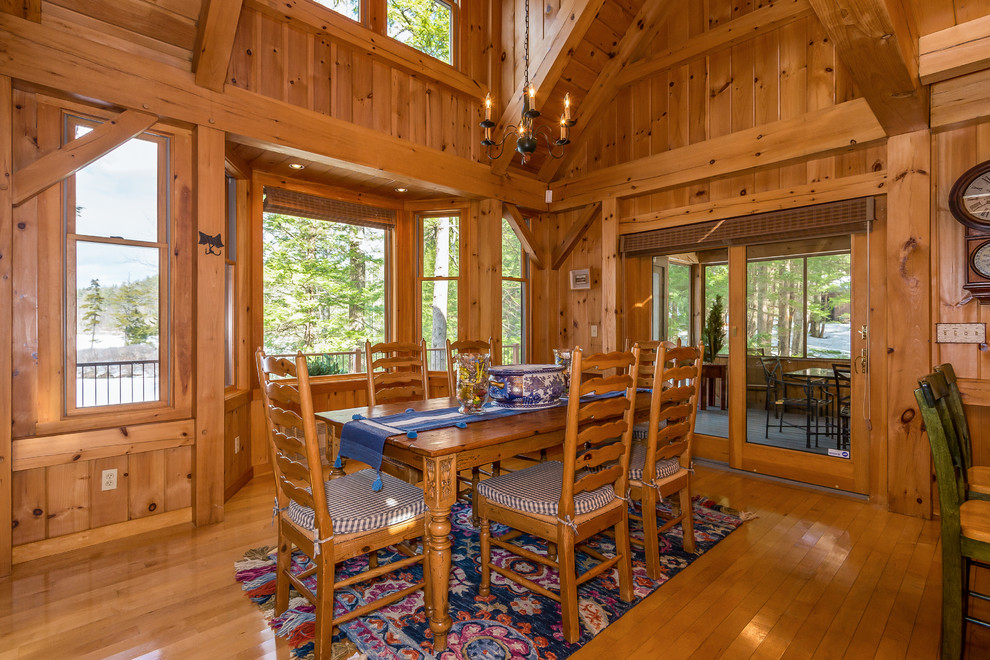 Exemple d'une salle à manger ouverte sur la cuisine montagne avec un mur marron, un sol en bois brun et un sol marron.