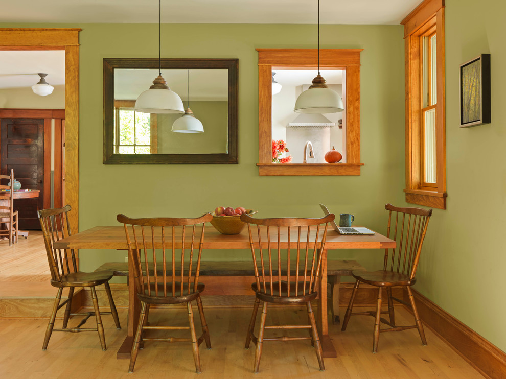 Diseño de comedor campestre de tamaño medio abierto con paredes verdes, suelo de madera clara y marco de chimenea de piedra