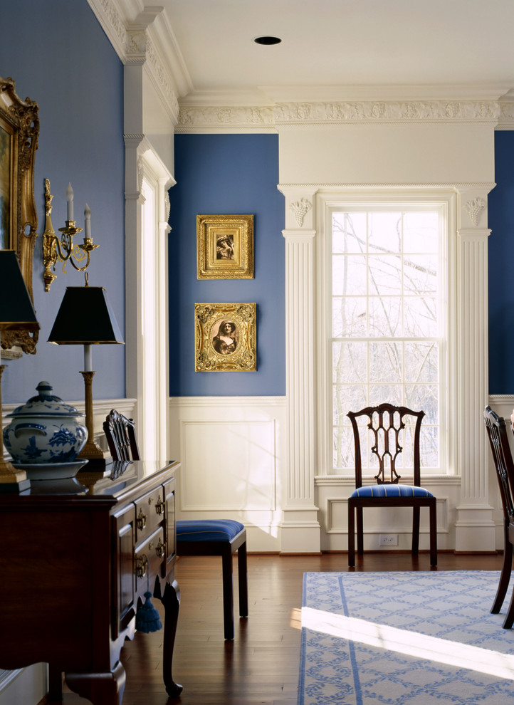 Cette image montre une salle à manger traditionnelle fermée et de taille moyenne avec un mur bleu, parquet foncé, aucune cheminée et un sol marron.