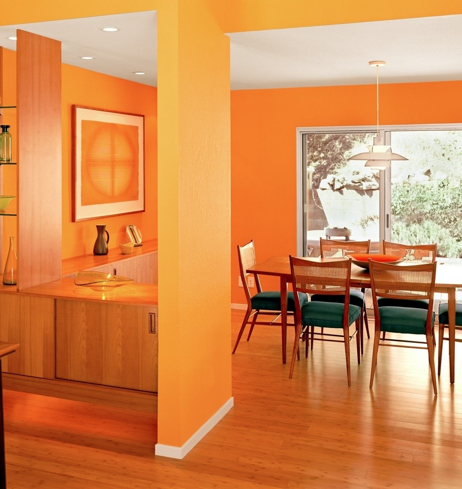Foto di una sala da pranzo aperta verso la cucina minimal di medie dimensioni con pareti arancioni, parquet chiaro, nessun camino e pavimento marrone