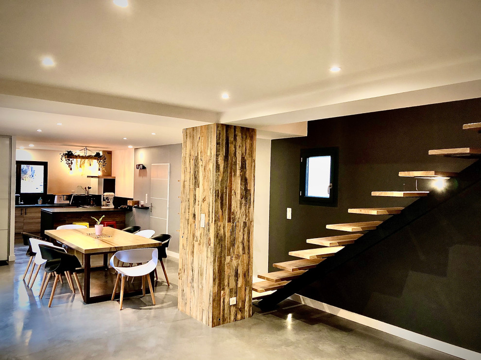 Идея дизайна: гостиная-столовая среднего размера в современном стиле с черными стенами, бетонным полом и серым полом без камина