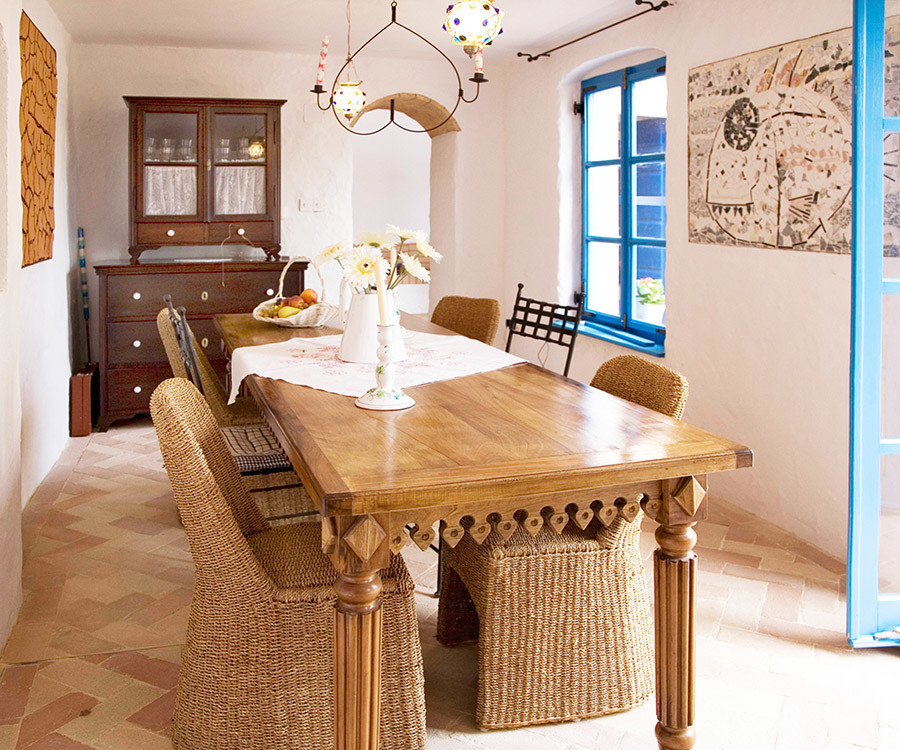 Réalisation d'une petite salle à manger ouverte sur la cuisine méditerranéenne avec un mur blanc, un sol en brique et un manteau de cheminée en bois.