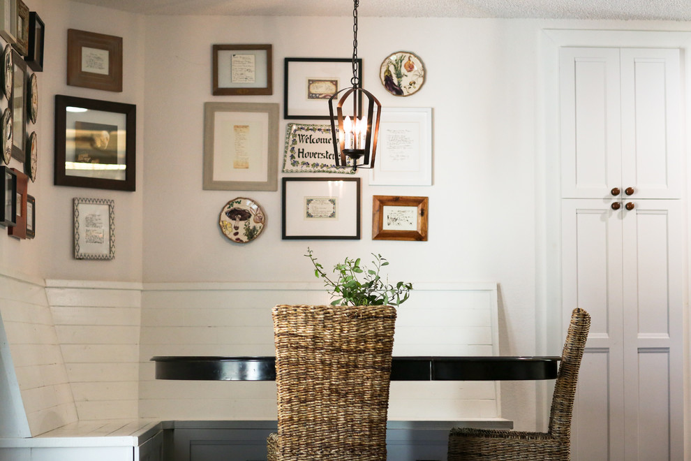 Cette image montre une petite salle à manger ouverte sur la cuisine rustique avec un mur blanc, parquet foncé et un sol marron.