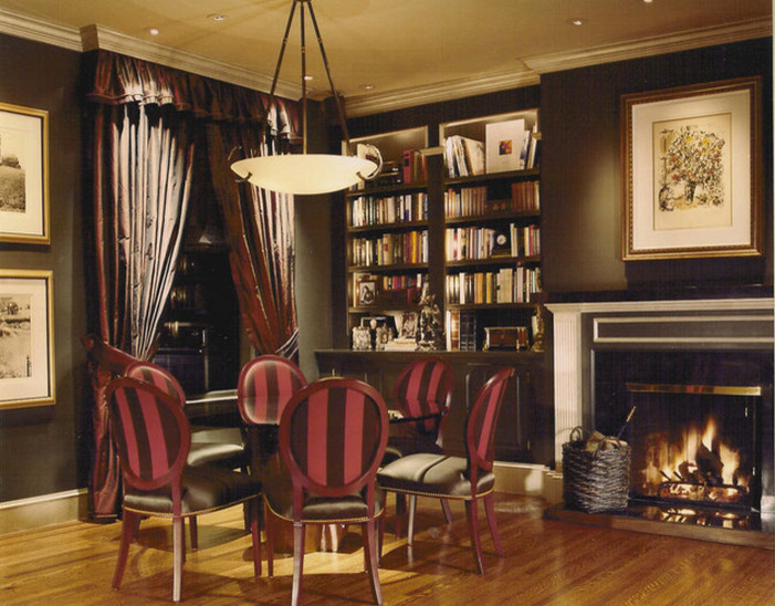 Exemple d'une salle à manger ouverte sur le salon chic de taille moyenne avec un mur noir, un sol en bois brun et une cheminée standard.