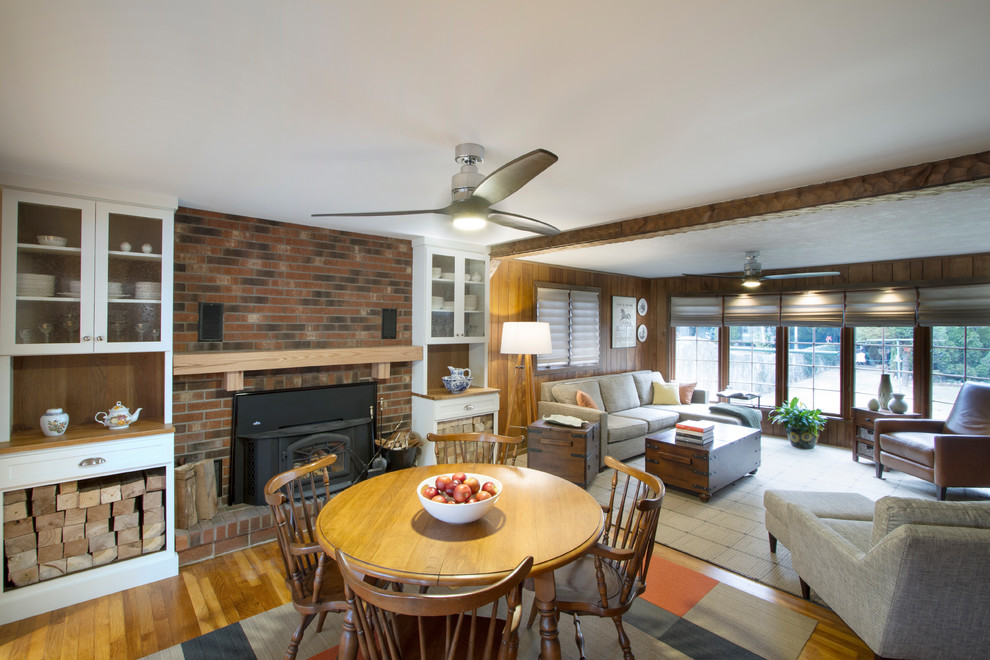 Exemple d'une salle à manger ouverte sur le salon montagne de taille moyenne avec un mur marron, un sol en bois brun, un poêle à bois, un manteau de cheminée en brique et un sol marron.