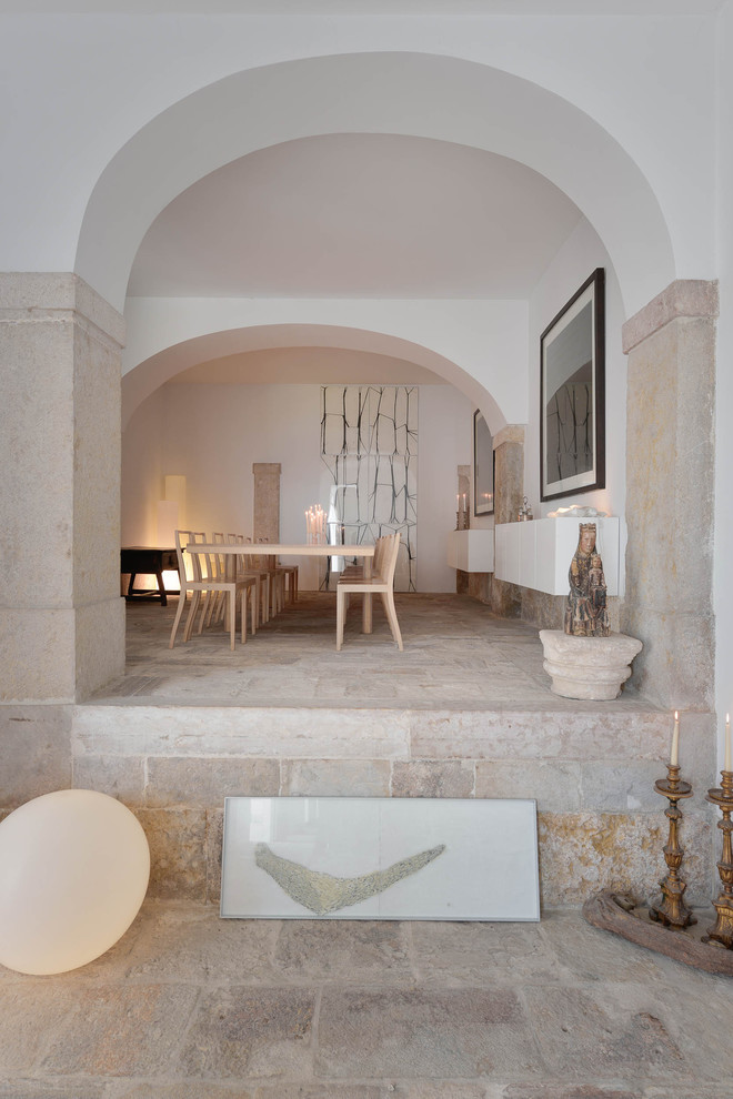 Exemple d'une grande salle à manger méditerranéenne avec un mur beige, un sol en calcaire, une cheminée d'angle et un manteau de cheminée en pierre.
