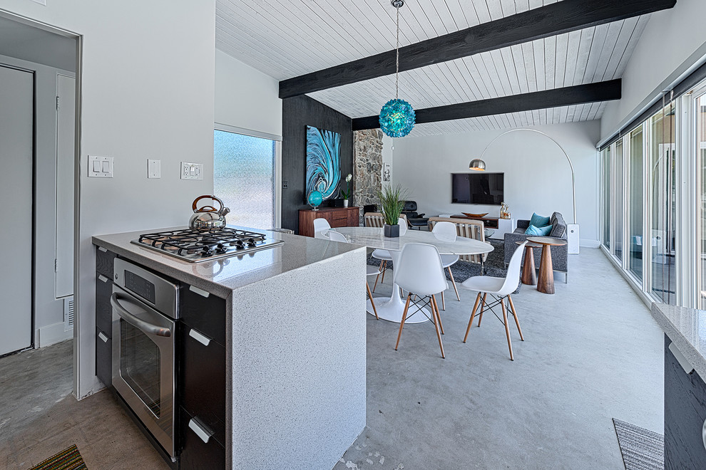 他の地域にある高級な中くらいなミッドセンチュリースタイルのおしゃれなダイニングキッチン (白い壁、コンクリートの床、標準型暖炉、石材の暖炉まわり) の写真