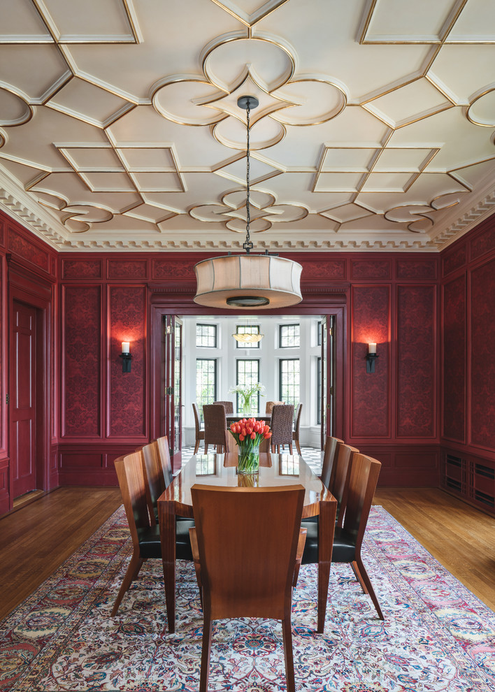 Cette image montre une salle à manger traditionnelle fermée avec un mur rouge, un sol en bois brun et un sol marron.