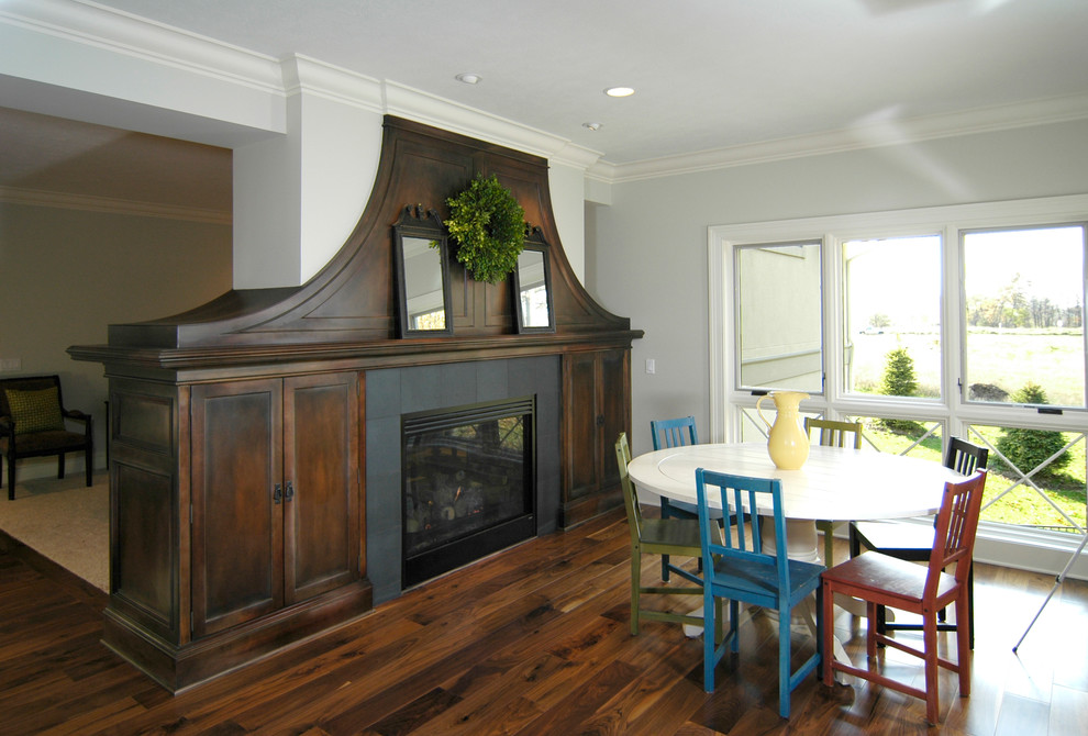 Country dark wood floor and brown floor kitchen/dining room combo photo in Grand Rapids with white walls, a two-sided fireplace and a tile fireplace