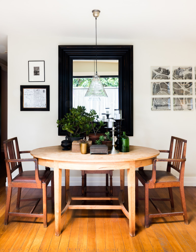 Esempio di una piccola sala da pranzo aperta verso la cucina boho chic con pareti bianche, pavimento in legno massello medio e pavimento marrone