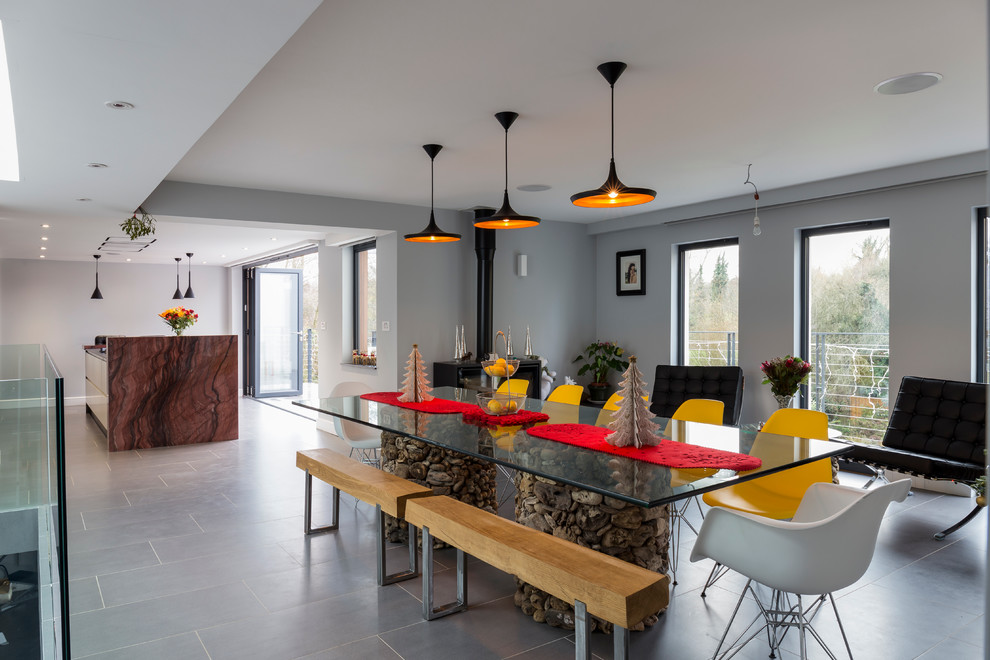 Foto di una sala da pranzo aperta verso la cucina contemporanea con pareti grigie e stufa a legna