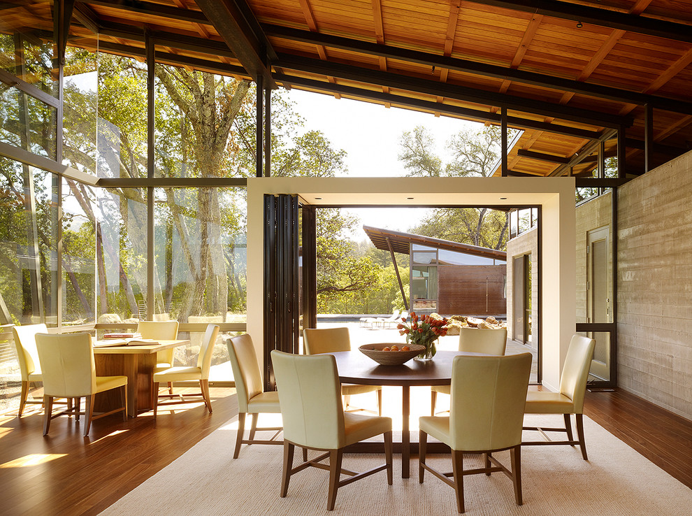 Idées déco pour une salle à manger ouverte sur le salon contemporaine avec un mur gris, un sol en bois brun et un sol beige.