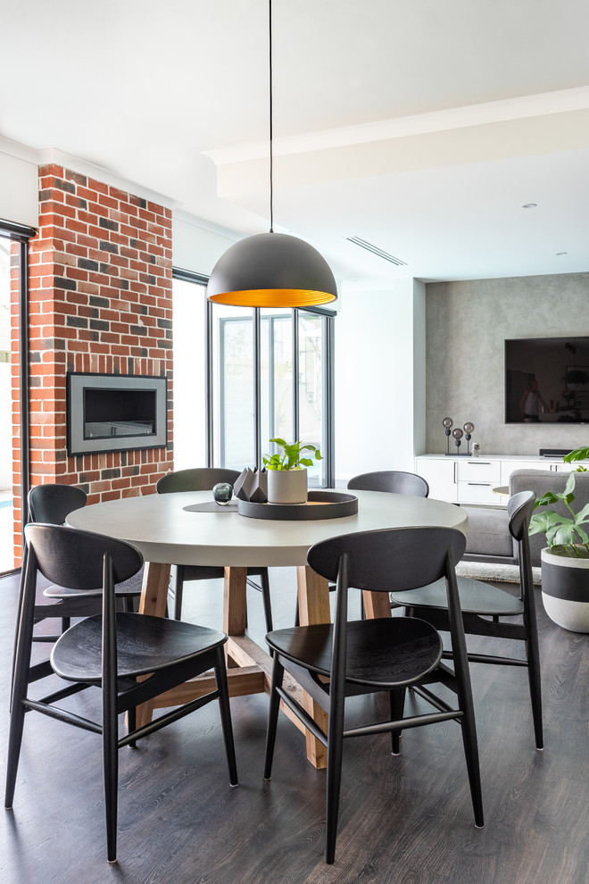 Inspiration pour une salle à manger ouverte sur le salon design avec un mur blanc, parquet foncé, une cheminée ribbon, un manteau de cheminée en brique et un sol marron.