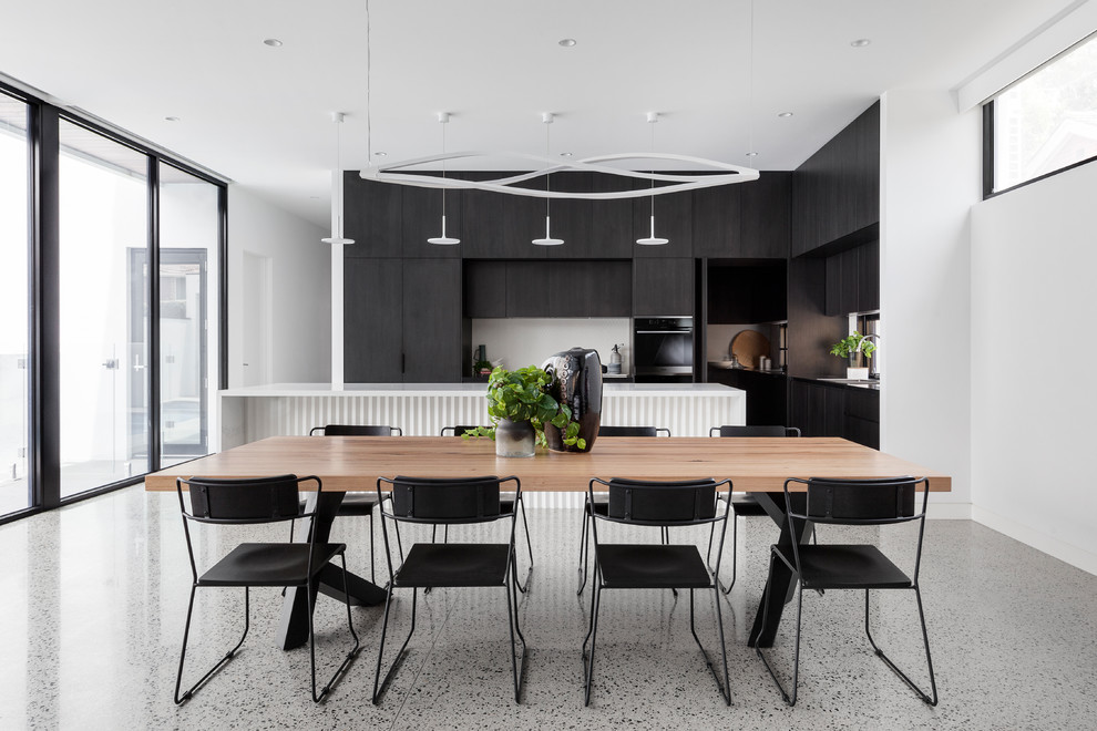 Exemple d'une grande salle à manger ouverte sur la cuisine moderne avec un mur blanc et un sol gris.