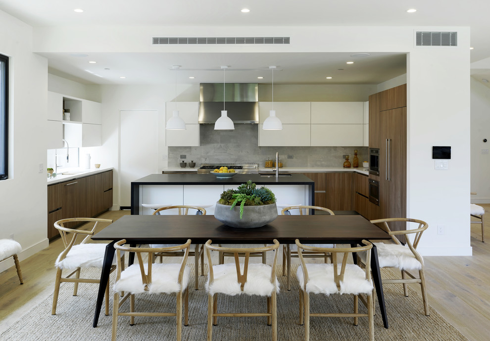 Cette image montre une salle à manger ouverte sur la cuisine design avec un mur blanc, parquet clair et un sol beige.
