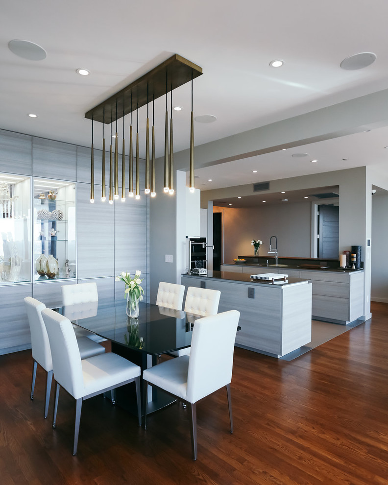Inspiration pour une salle à manger ouverte sur la cuisine design de taille moyenne avec un mur gris, parquet foncé, un sol marron et éclairage.