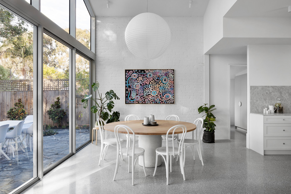 Idee per una sala da pranzo aperta verso la cucina contemporanea con pavimento in cemento, pareti bianche e pavimento grigio