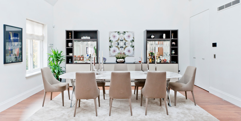 Idée de décoration pour une salle à manger design avec un mur blanc et un sol en bois brun.