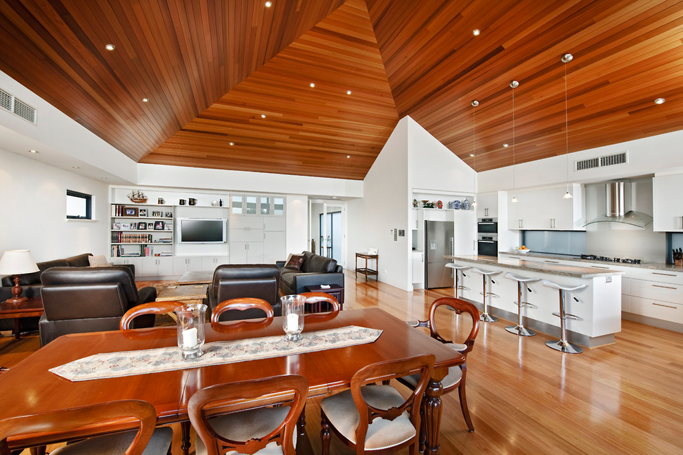 Imagen de comedor moderno abierto con paredes blancas y suelo de madera en tonos medios