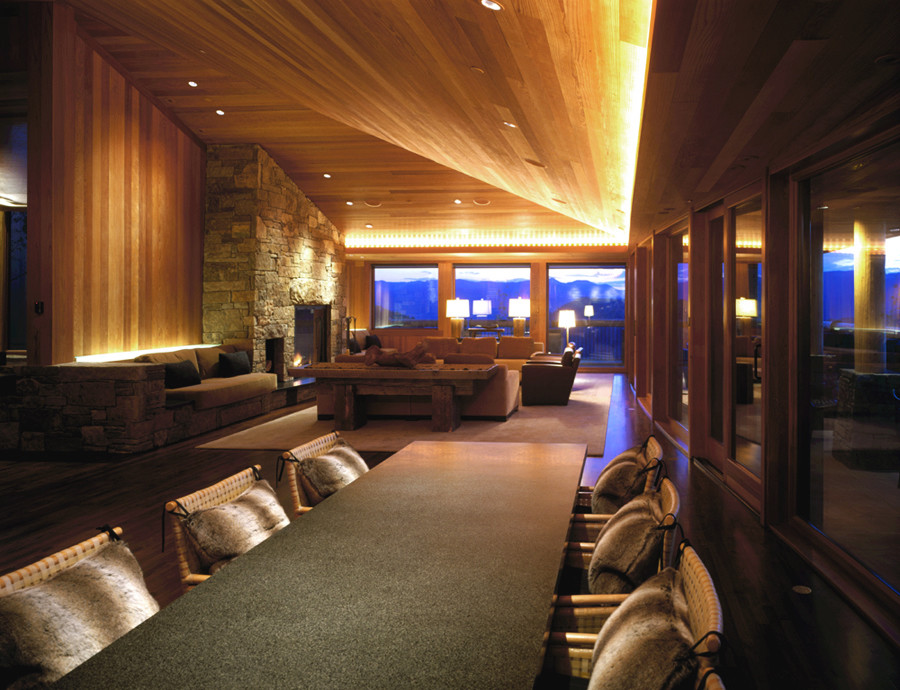 Idée de décoration pour une salle à manger ouverte sur le salon minimaliste avec un sol en bois brun, une cheminée standard et un manteau de cheminée en pierre.