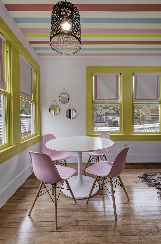 Cette image montre une salle à manger ouverte sur le salon bohème avec un mur blanc, parquet clair et un sol marron.