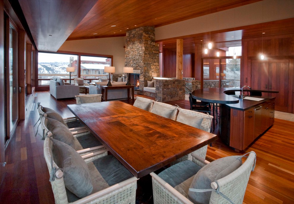 На фото: большая гостиная-столовая в стиле модернизм с паркетным полом среднего тона, угловым камином и фасадом камина из камня с