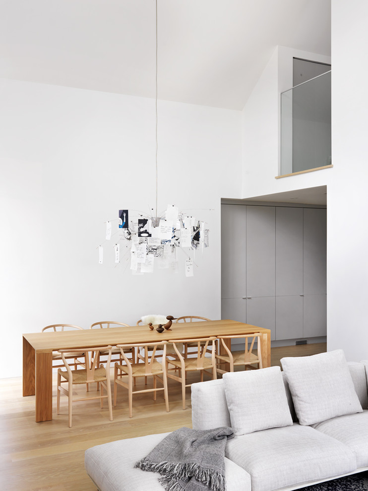Cette image montre une salle à manger minimaliste avec un mur blanc et un sol en bois brun.