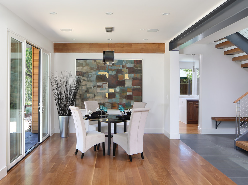 Ejemplo de comedor contemporáneo abierto con paredes blancas y suelo de madera en tonos medios