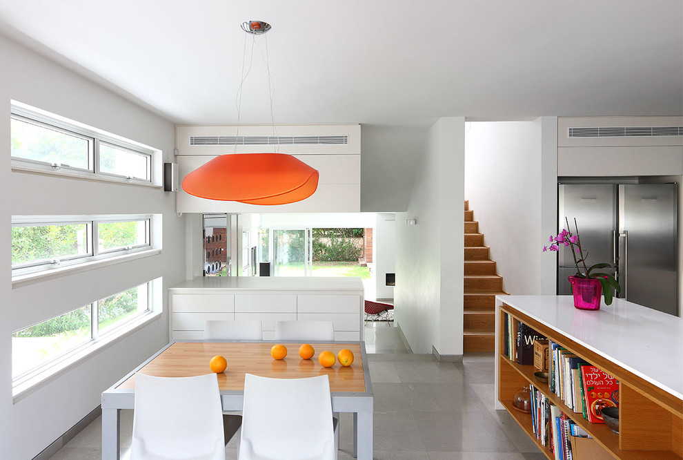 Immagine di una piccola sala da pranzo aperta verso la cucina minimalista con pareti bianche, pavimento in pietra calcarea e nessun camino