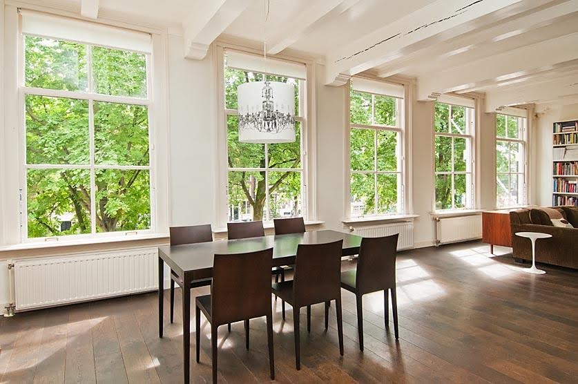 Design ideas for a medium sized scandi open plan dining room in Amsterdam with white walls, dark hardwood flooring, no fireplace, a stone fireplace surround and brown floors.