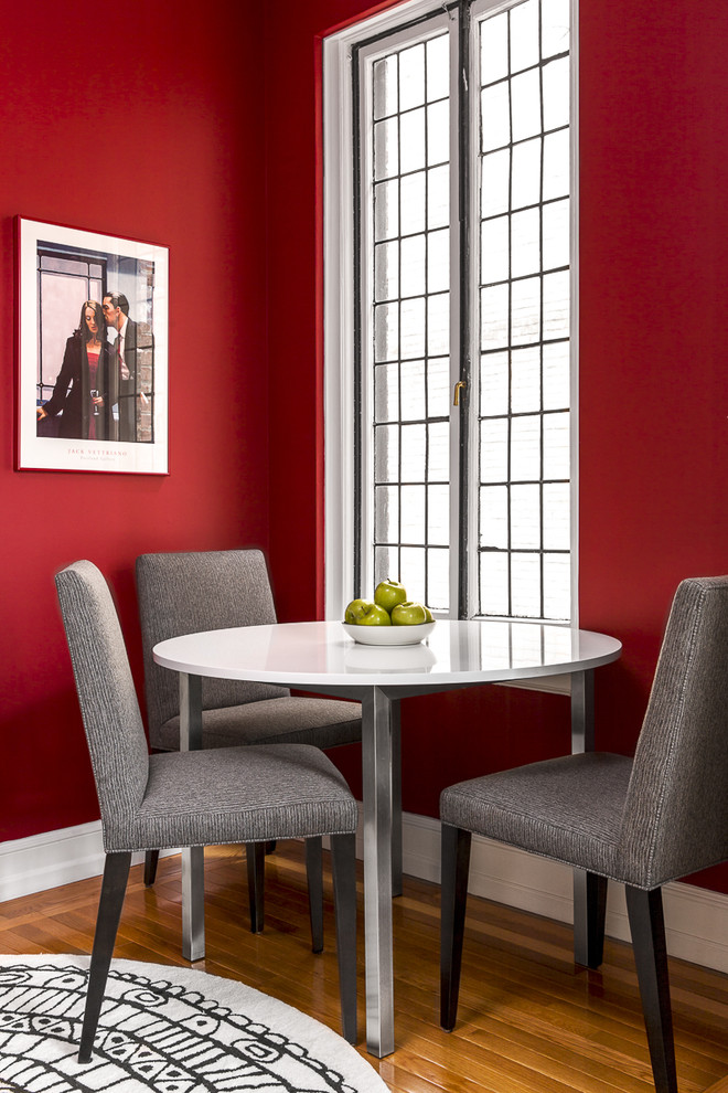 Modelo de comedor minimalista pequeño cerrado con paredes rojas y suelo de madera en tonos medios