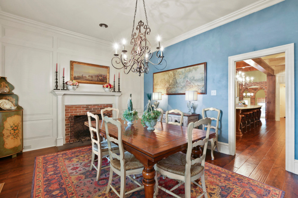 Immagine di una sala da pranzo con pareti blu, pavimento in legno massello medio, camino classico, cornice del camino in legno e pavimento marrone