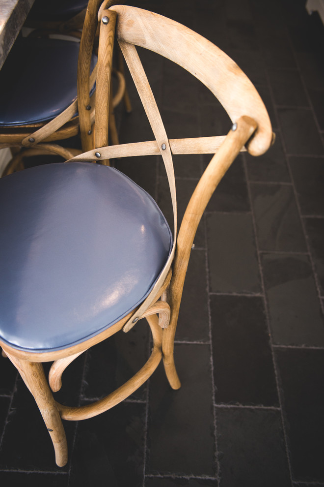 Immagine di una sala da pranzo aperta verso la cucina country di medie dimensioni con pareti blu, pavimento con piastrelle in ceramica, nessun camino e pavimento nero