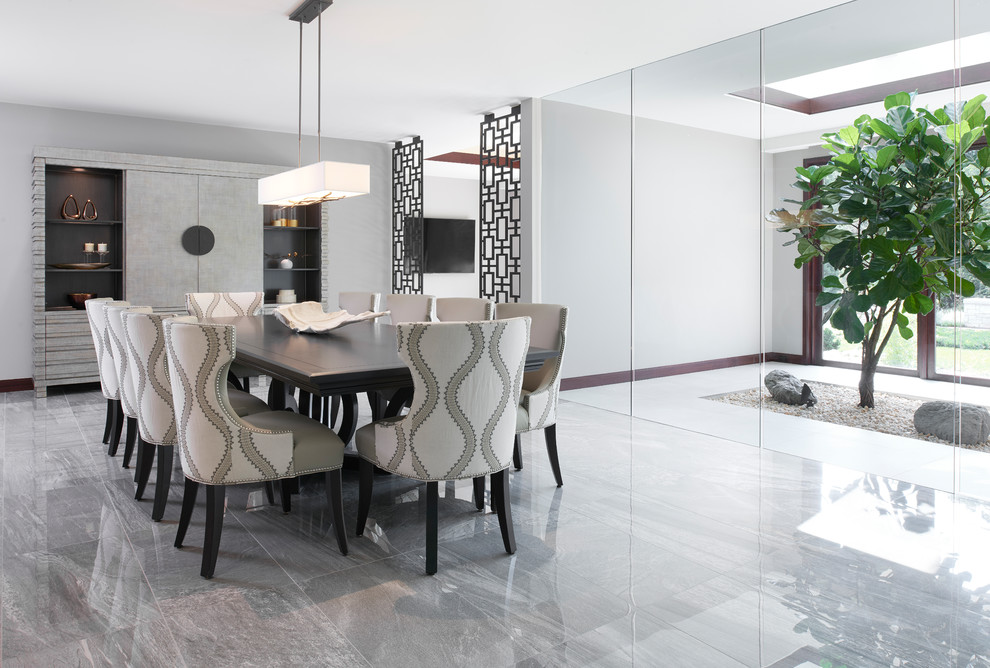 Cette image montre une salle à manger ouverte sur la cuisine design avec un mur gris et un sol gris.